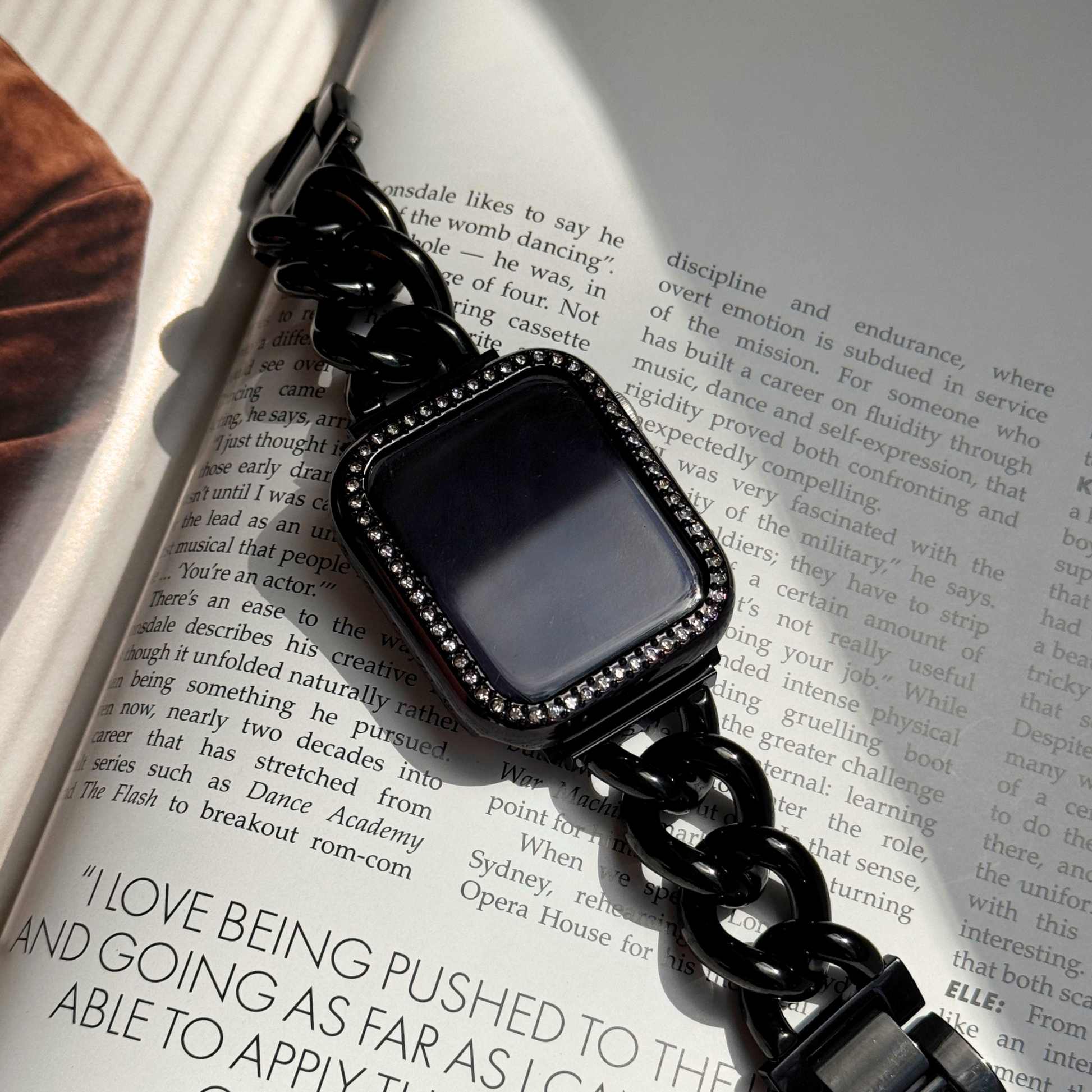 Black chain-strap smartwatch on an open book with a black rhinestone apple watch case