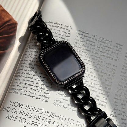 Black chain-strap smartwatch on an open book with a black rhinestone apple watch case