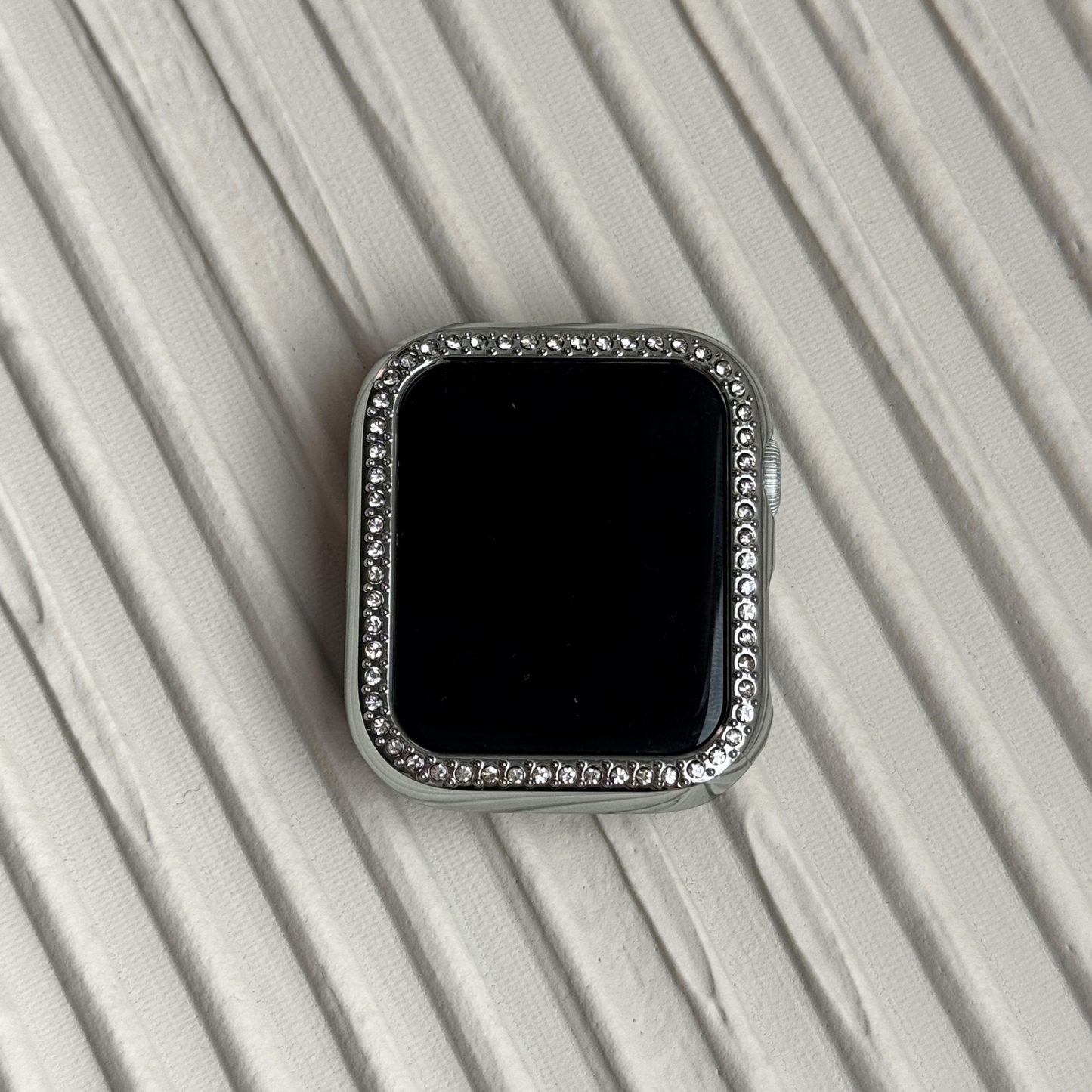 silver rhinestone apple watch case on a textured surface