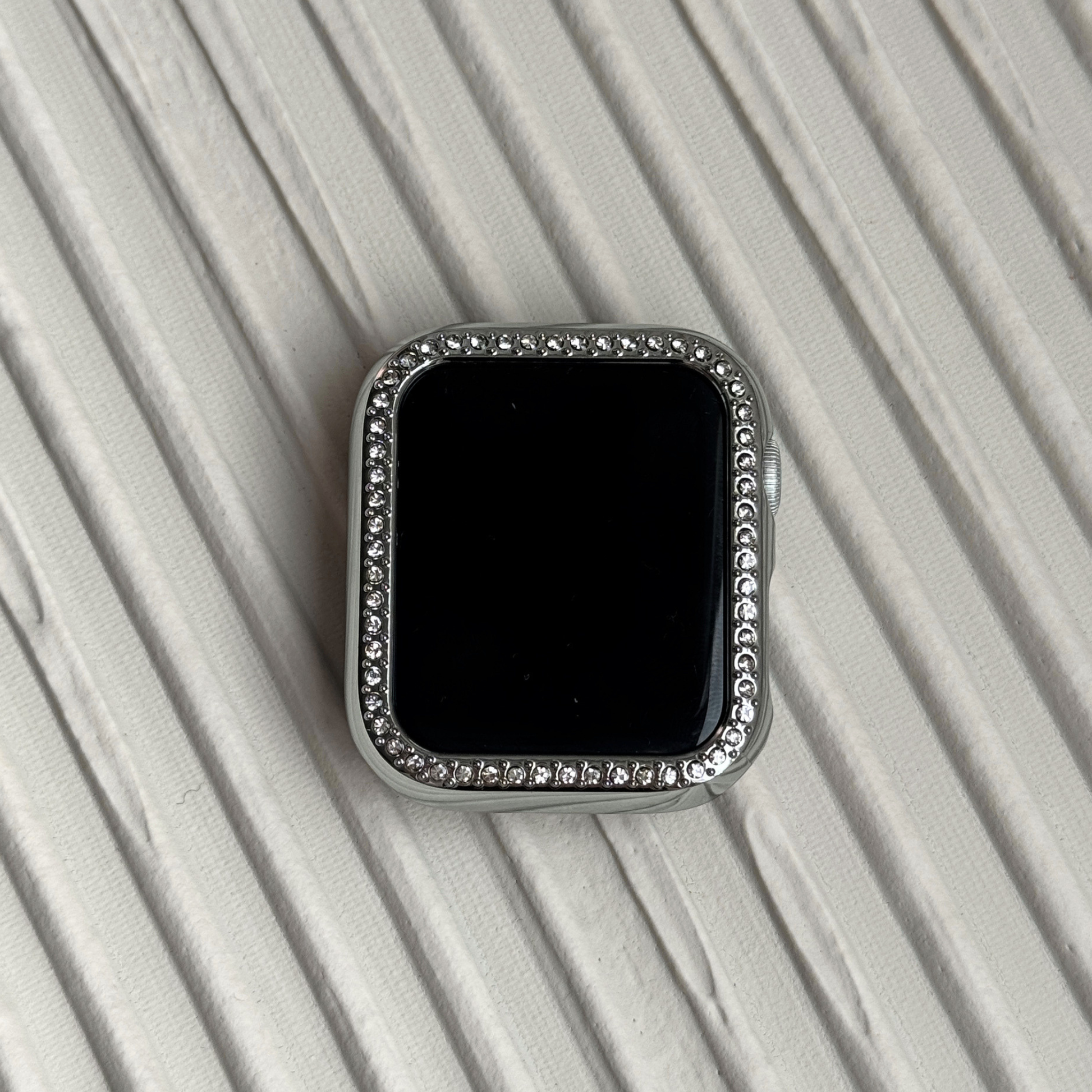 silver rhinestone apple watch case on a textured surface