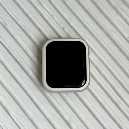 Starlight stainless steel Apple Watch case cover shown on a ribbed white surface. Refined protective bumper, available for Apple Watch 38mm to 49mm, Series 1-11, SE and Ultra