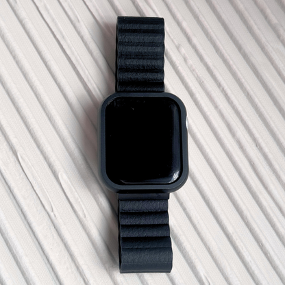Black stainless steel Apple Watch case cover shown on a ribbed white surface. Premium protective bumper with a refined finish, available for Apple Watch 38mm to 49mm, Series 1-11, SE and Ultra