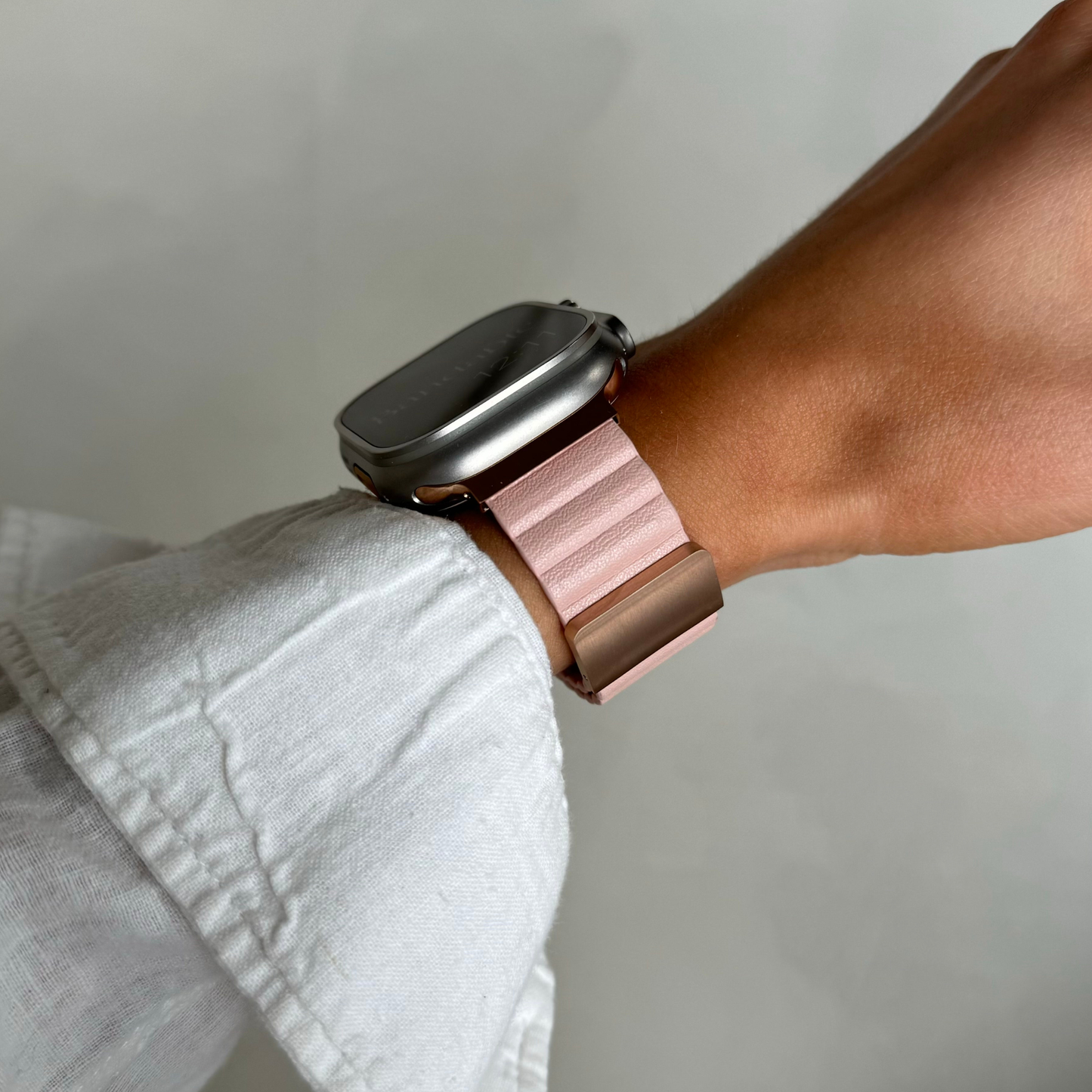 Pink ribbed vegan leather Apple Watch band worn on a wrist with a linen cuff. Magnetic iWatch strap with no buckle to line up, compatible with Apple Watch 38mm to 49mm, Series 1-11, SE and Ultra