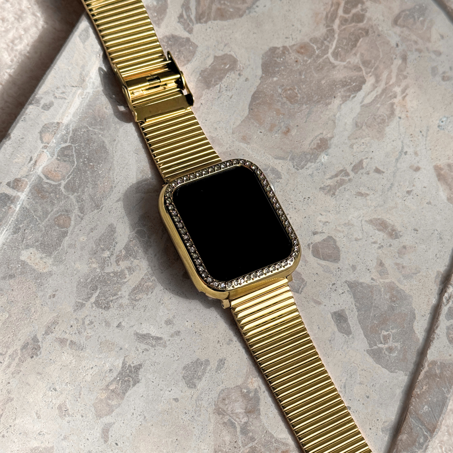 Apple watch with on a marble surface with a gold rhinestone apple watch case