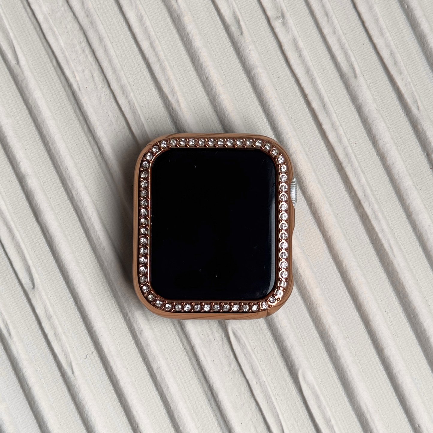 rose Gold rhinestone apple watch case on a textured surface