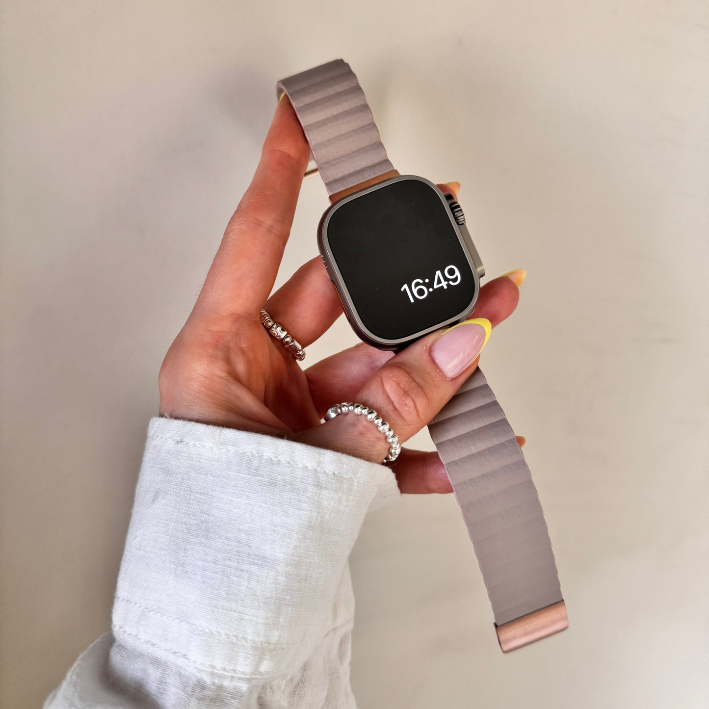 Starlight ribbed vegan leather Apple Watch band held in a hand against a cream wall. Soft magnetic iWatch strap, compatible with Apple Watch 38mm to 49mm, Series 1-11, SE and Ultra