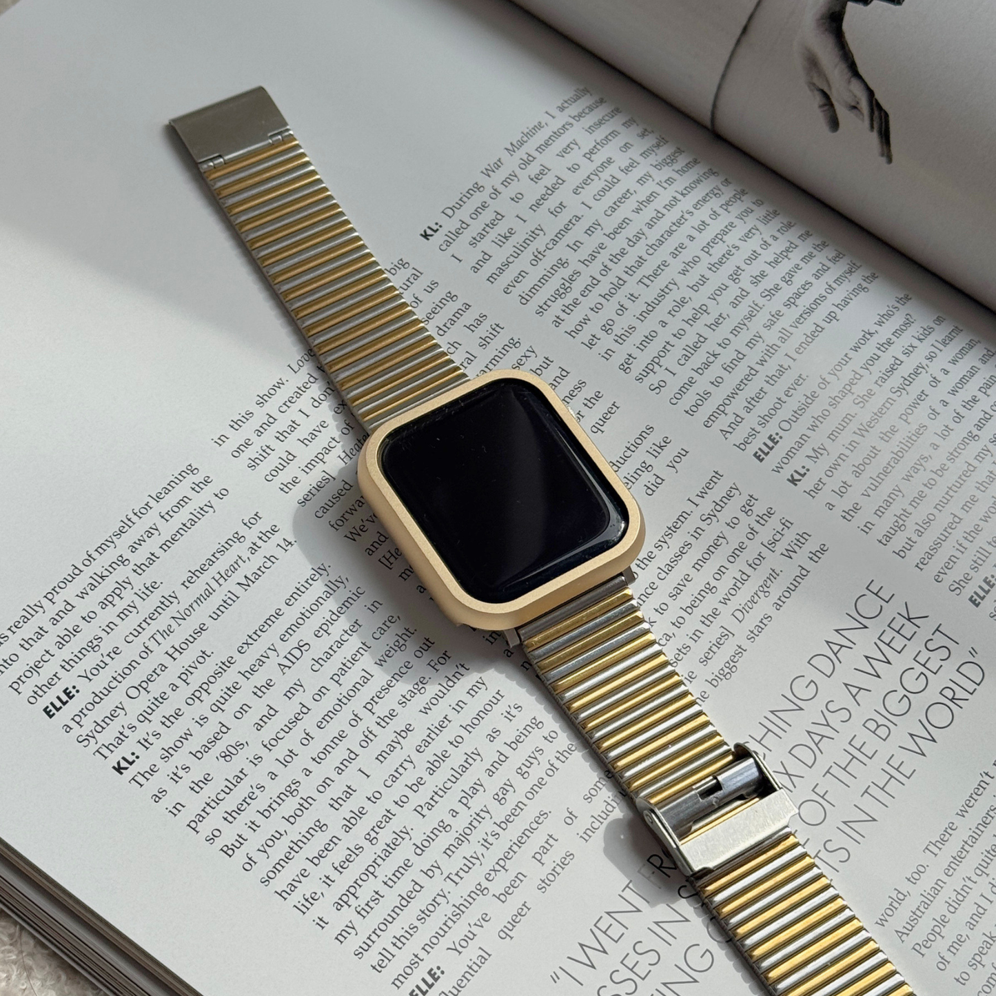Gold stainless steel Apple Watch case cover shown on an open magazine with a mesh band. Durable protective bumper, available for Apple Watch 38mm to 49mm, Series 1-11, SE and Ultra