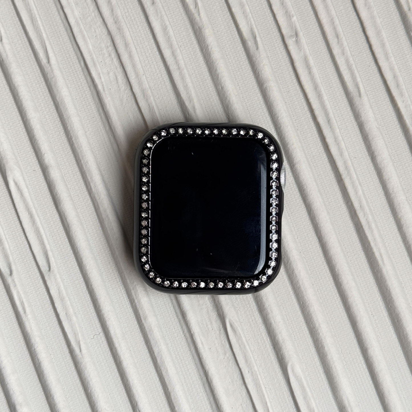 black rhinestone apple watch case on a textured surface