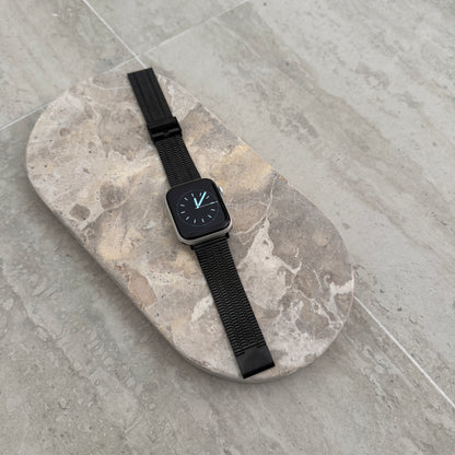 Black flat woven Apple Watch band lying flat on a stone tray. Lightweight stainless steel iWatch strap, compatible with Apple Watch 38mm to 49mm, Series 1-11, SE and Ultra