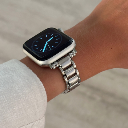 Silver slim link Apple Watch band worn on a wrist with a white linen sleeve. Sleek metal iWatch strap with a clean modern aesthetic, compatible with Apple Watch 38mm to 49mm, Series 1-11, SE and Ultra