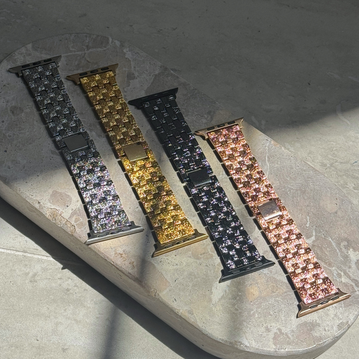 Silver, gold, black and rose gold baroque Apple Watch bands laid out on stone in sunlight. Vintage inspired metal iWatch straps, compatible with Apple Watch 38mm to 49mm, Series 1-11, SE and Ultra