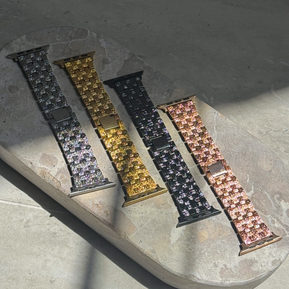 Silver, gold, black and rose gold baroque Apple Watch bands laid out on stone in sunlight. Vintage inspired metal iWatch straps, compatible with Apple Watch 38mm to 49mm, Series 1-11, SE and Ultra