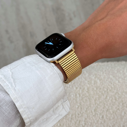 Gold ribbed loop Apple Watch band worn on a wrist with a white linen cuff. Waterproof stainless steel iWatch bracelet, easy to resize for a perfect fit, compatible with Apple Watch 38mm to 49mm, Series 1-11, SE and Ultra