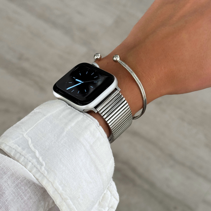 Silver ribbed loop Apple Watch band worn beside a thin cuff bangle. Waterproof stainless steel iWatch strap, easy to resize, compatible with Apple Watch 38mm to 49mm, Series 1-11, SE and Ultra