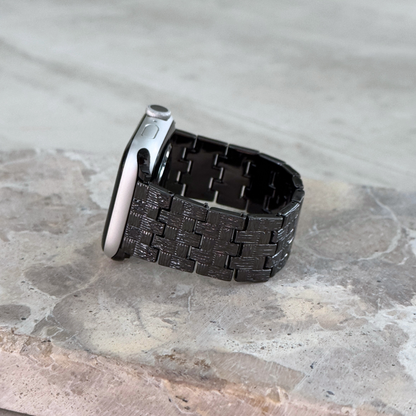 Black baroque pattern Apple Watch band propped upright on a stone surface. Metal iWatch strap with a vintage inspired look, compatible with Apple Watch 38mm to 49mm, Series 1-11, SE and Ultra