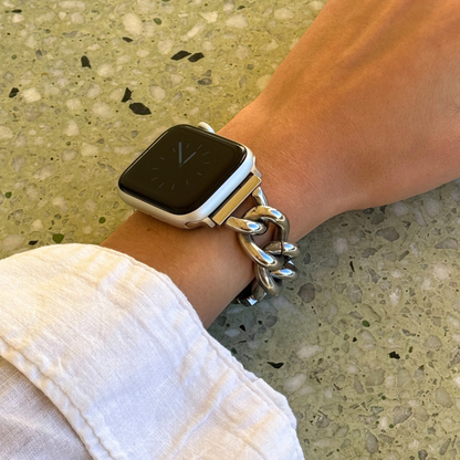 Silver chain link Apple Watch band worn on a wrist beside a linen cuff. Statement stainless steel iWatch armband with oversized links, compatible with Apple Watch 38mm to 49mm, Series 1-11, SE and Ultra