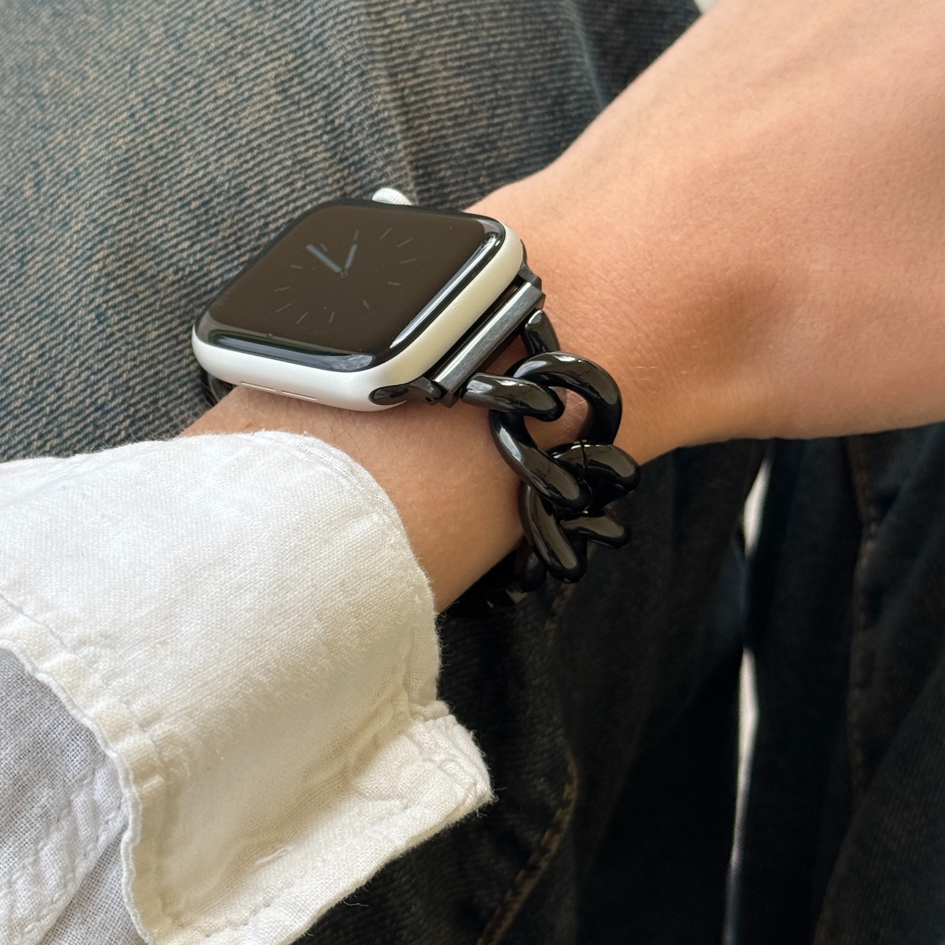 Black chain link Apple Watch band worn on a wrist over dark denim. Bold stainless steel iWatch bracelet with edge, compatible with Apple Watch 38mm to 49mm, Series 1-11, SE and Ultra