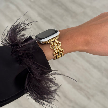 Gold chain link Apple Watch band worn with a feathered sleeve. Metal iWatch armband that complements every outfit, compatible with Apple Watch 38mm to 49mm, Series 1-11, SE and Ultra