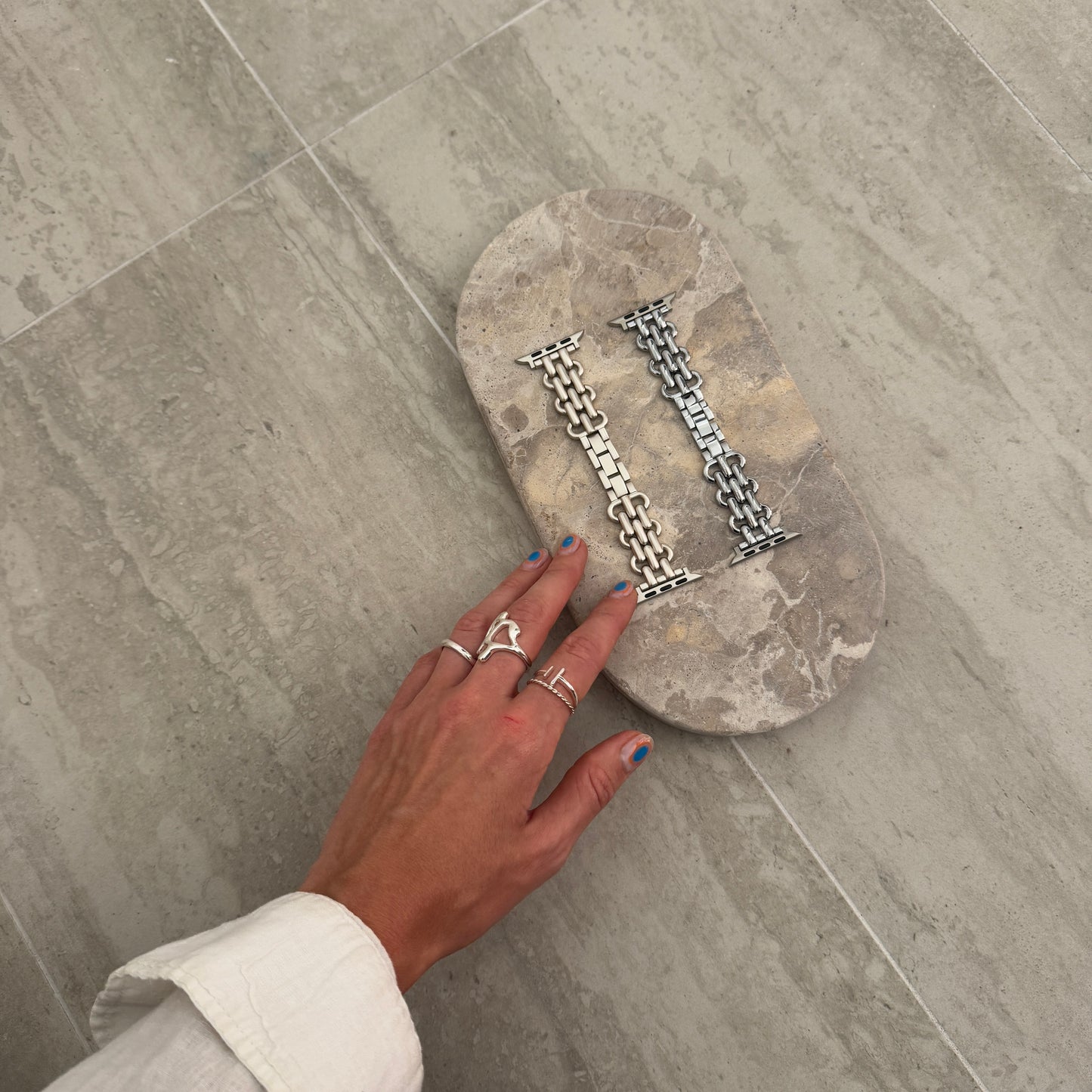 Silver and starlight chain link Apple Watch bands displayed on a stone tray. Fashionable metal iWatch straps, compatible with Apple Watch 38mm to 49mm, Series 1-11, SE and Ultra