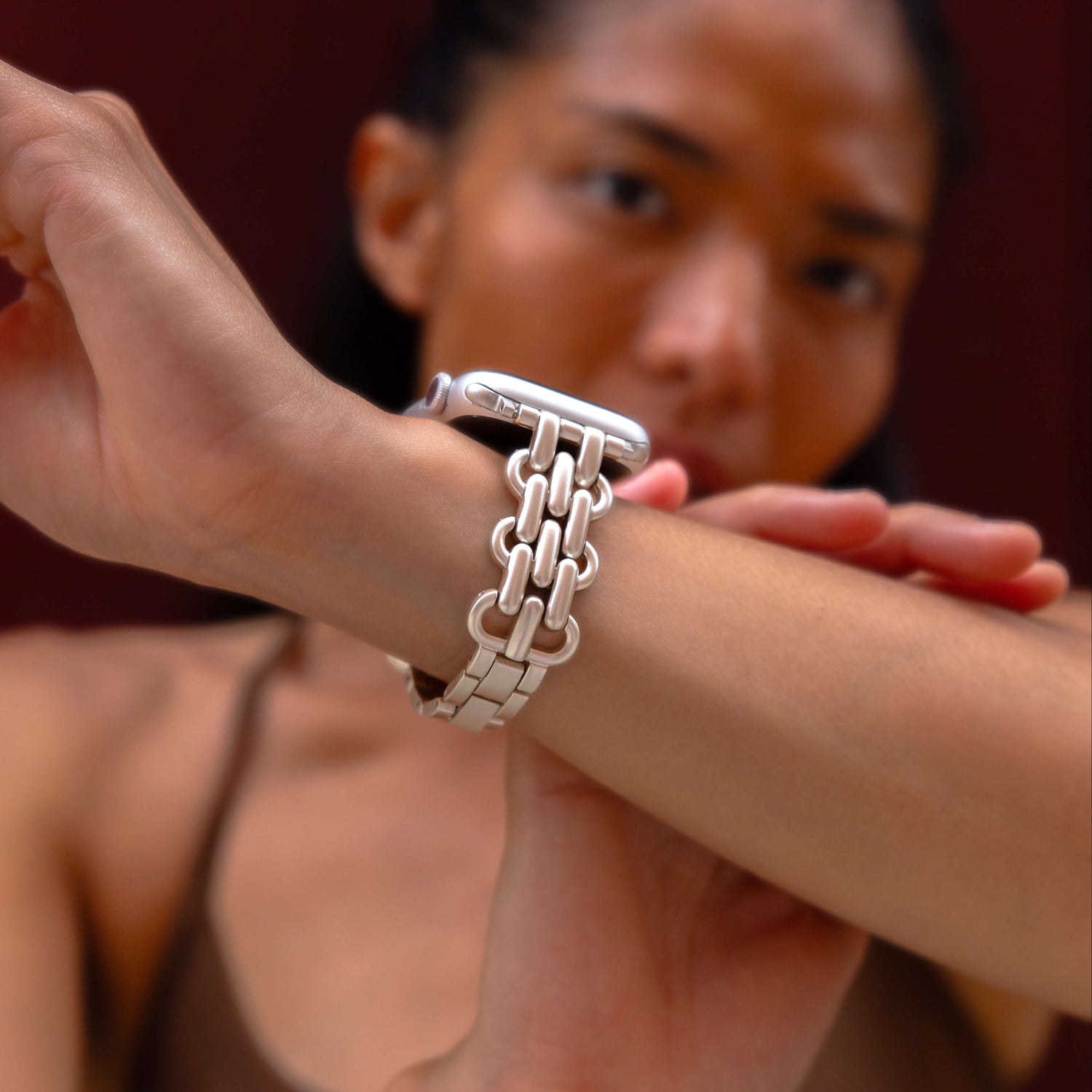 Starlight chain link Apple Watch band worn on a wrist against a deep red backdrop. Fashionable metal iWatch bracelet with a high polish shine, compatible with Apple Watch 38mm, 40mm, 41mm, 42mm, 44mm, 45mm, 46mm and 49mm, Series 1-11, SE and Ultra
