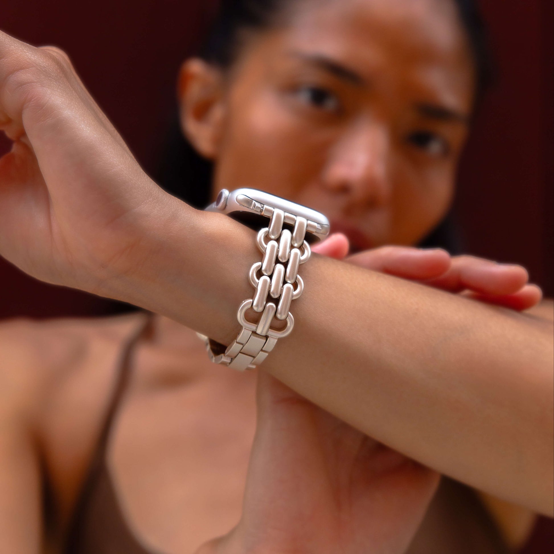 Starlight chain link Apple Watch band worn on a wrist against a deep red backdrop. Fashionable metal iWatch bracelet with a high polish shine, compatible with Apple Watch 38mm, 40mm, 41mm, 42mm, 44mm, 45mm, 46mm and 49mm, Series 1-11, SE and Ultra