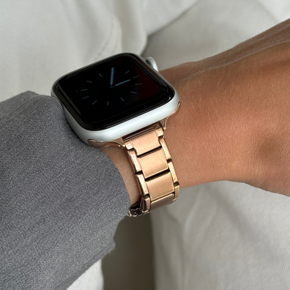 Rose gold slim link Apple Watch band worn on a wrist with a grey sleeve, stainless steel strap for Apple Watch 38mm to 49mm