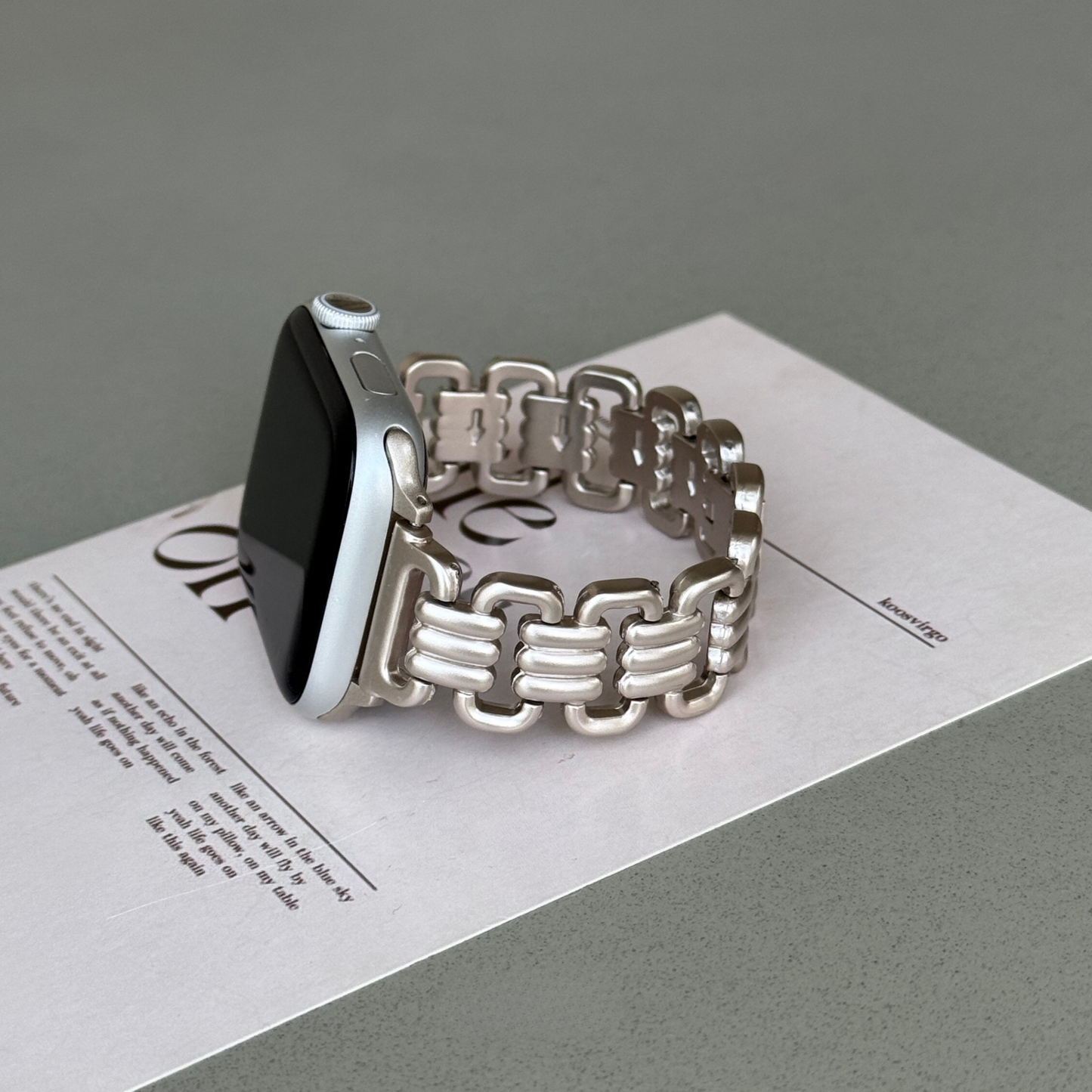 Starlight open link Apple Watch band propped on a printed card. Feminine high-end metal iWatch bracelet, compatible with Apple Watch 38mm, 40mm, 41mm, 42mm, 44mm, 45mm, 46mm and 49mm, Series 1-11, SE and Ultra