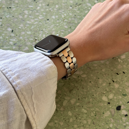 Silver rose gold pebble link Apple Watch band worn on a wrist against a green terrazzo background. Modern stainless steel iWatch armband, compatible with Apple Watch 38mm to 49mm, Series 1-11, SE and Ultra