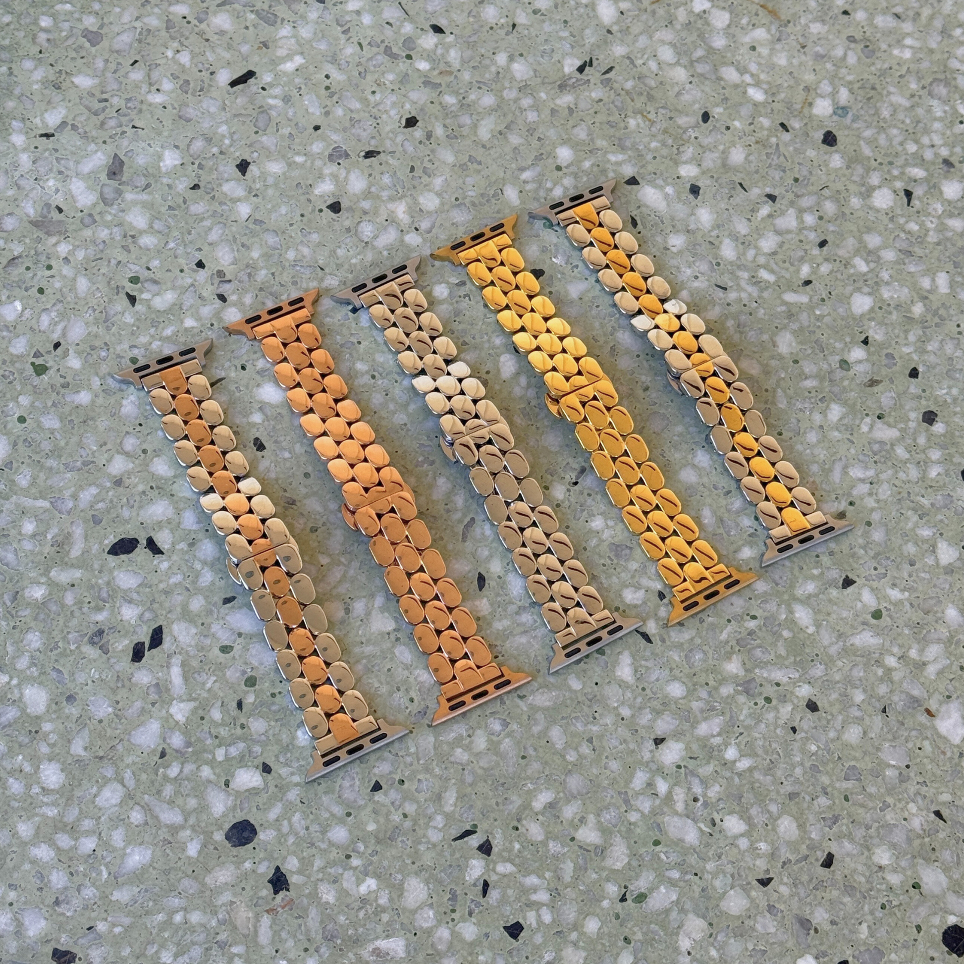 Silver, rose gold, gold, silver rose gold and silver gold pebble link Apple Watch bands laid out on terrazzo. Slim stainless steel iWatch straps, compatible with Apple Watch 38mm to 49mm, Series 1-11, SE and Ultra