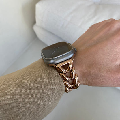 Rose gold chunky chain Apple Watch band worn with a beige sleeve on a cushion. Metal iWatch bracelet that elevates any outfit, compatible with Apple Watch 38mm to 49mm, Series 1-11, SE and Ultra