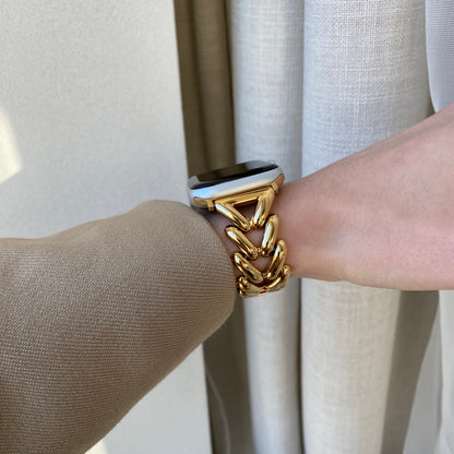 Gold chunky chain Apple Watch band worn with a beige sleeve beside a linen curtain. Unique metal iWatch armband, compatible with Apple Watch 38mm to 49mm, Series 1-11, SE and Ultra