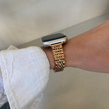 Rose gold woven link Apple Watch band worn on a wrist with a white linen cuff, stainless steel strap for Apple Watch 38mm to 49mm