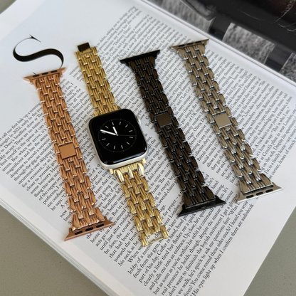 Rose gold, gold, black and silver link Apple Watch bands laid out on a magazine. Sleek metal iWatch straps and armbands, compatible with Apple Watch 38mm to 49mm, Series 1-11, SE and Ultra