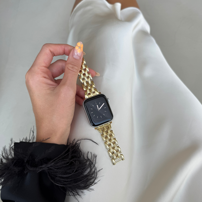 Gold link Apple Watch band held in a hand above white satin. Sleek metal iWatch strap, compatible with Apple Watch 38mm to 49mm, Series 1-11, SE and Ultra
