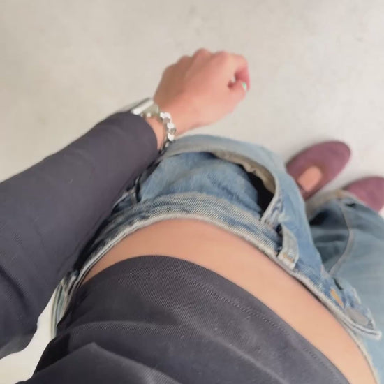 a video of a woman wearing a silver chunky Apple Watch band, paired with a top, blue jeans and brown mary-jane flats