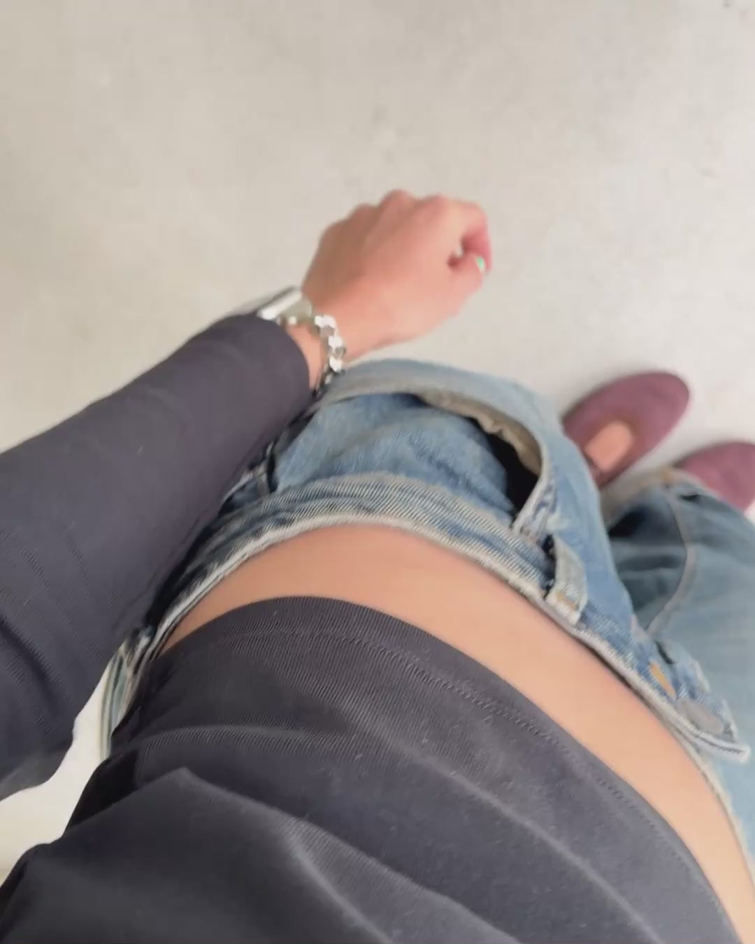 a video of a woman wearing a silver chunky Apple Watch band, paired with a top, blue jeans and brown mary-jane flats