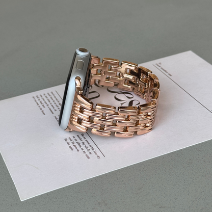 Rose gold link Apple Watch band propped upright on a printed card. Fashion forward metal iWatch armband, compatible with Apple Watch 38mm to 49mm, Series 1-11, SE and Ultra
