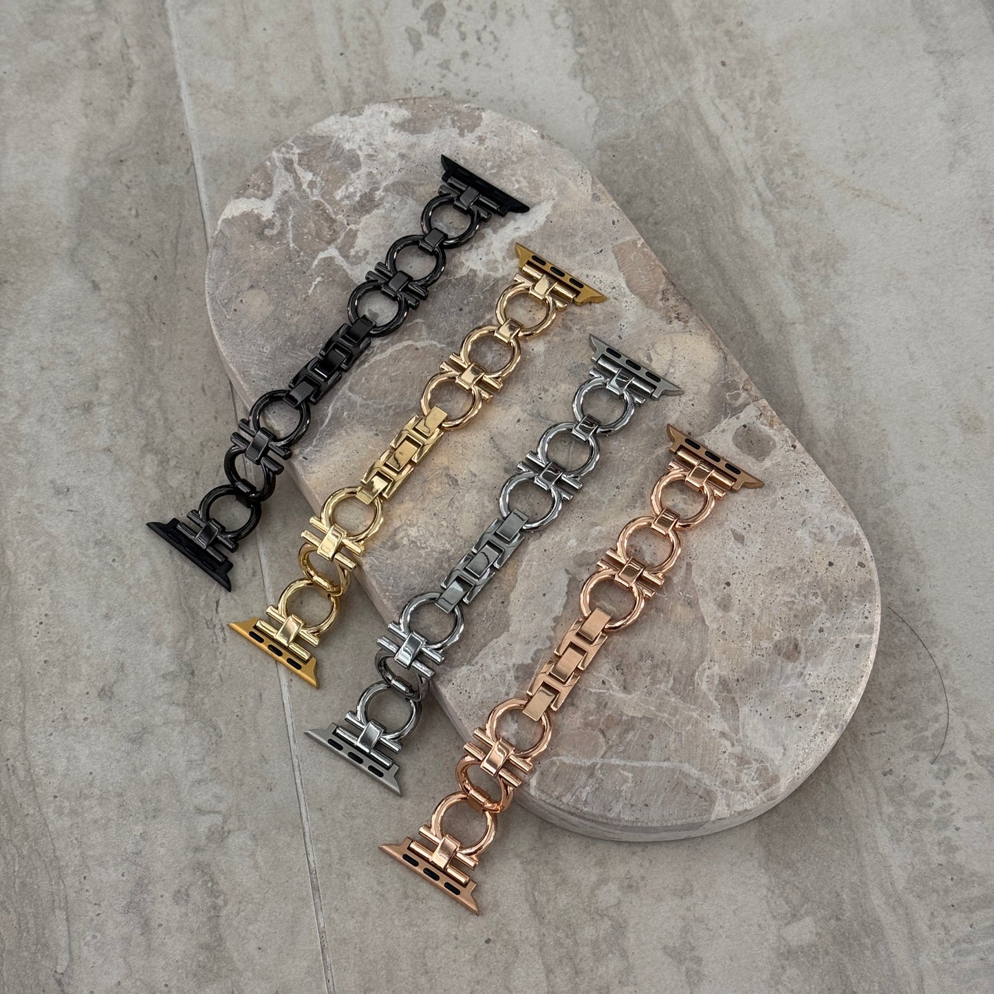 Black, gold, silver and rose gold circle link Apple Watch bands laid on a stone tray. Slim metal iWatch straps and bracelets, compatible with Apple Watch 38mm to 49mm, Series 1-11, SE and Ultra