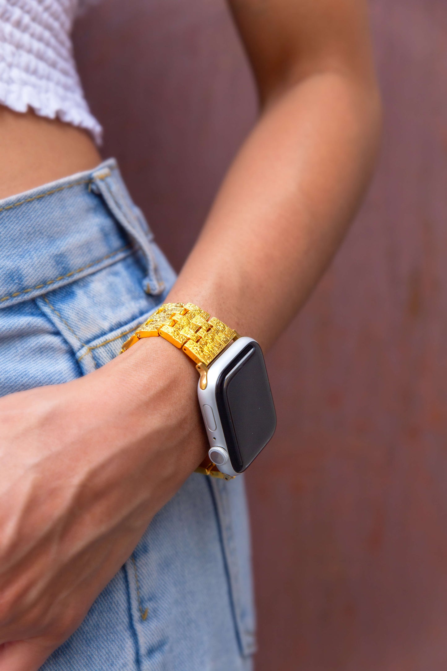 Gold baroque pattern Apple Watch band worn with denim by a woman outdoors. Luxurious metal iWatch strap, compatible with Apple Watch 38mm to 49mm, Series 1-11, SE and Ultra