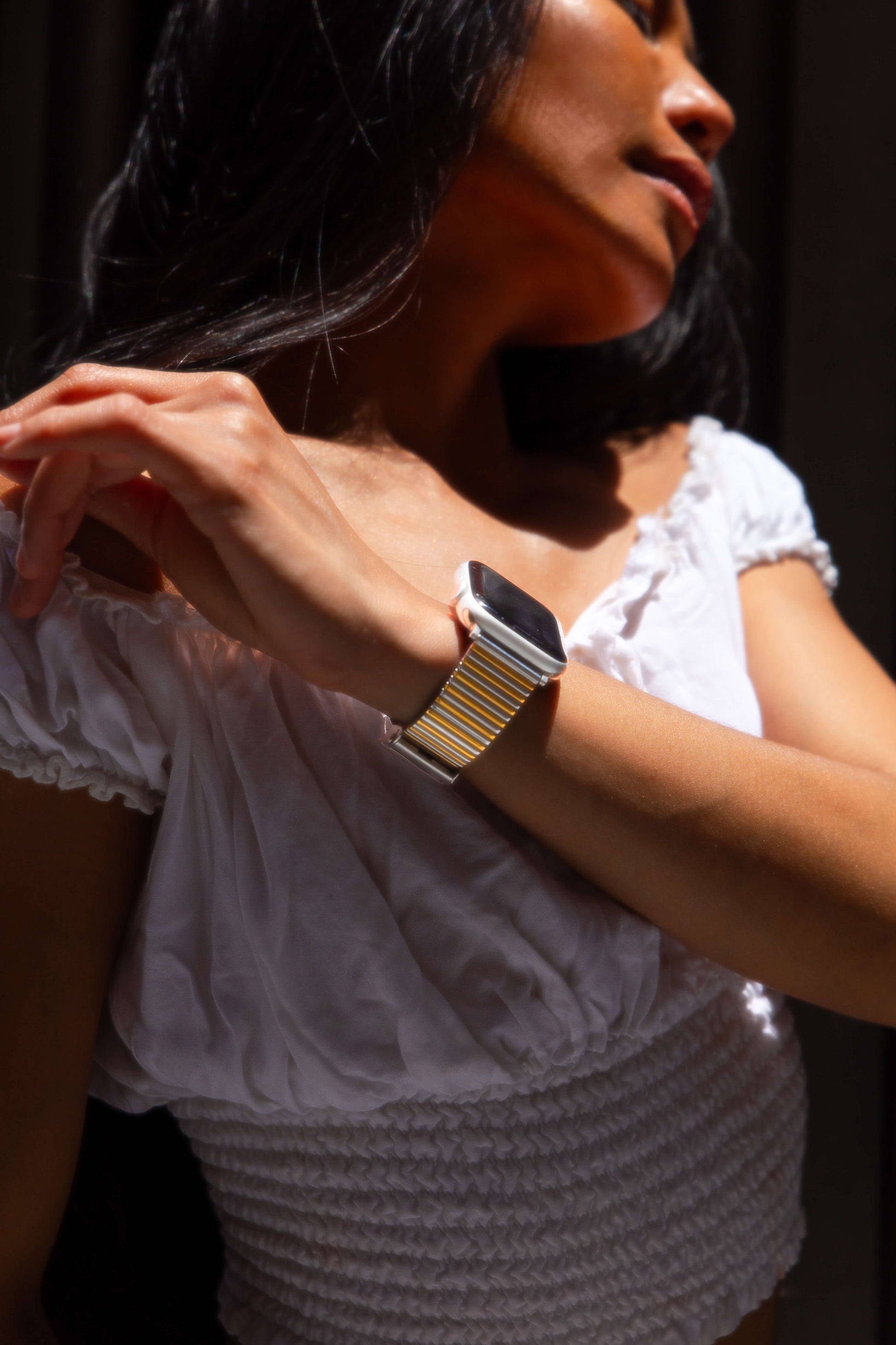 Silver gold ribbed loop Apple Watch band worn by a woman in a white top. Chic stainless steel iWatch strap, compatible with Apple Watch 38mm to 49mm, Series 1-11, SE and Ultra