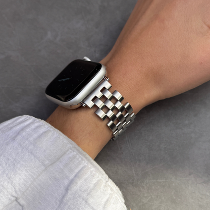 Silver multi link Apple Watch band worn on a wrist with a white linen sleeve. Unisex brushed matte stainless steel iWatch bracelet, compatible with Apple Watch 38mm to 49mm, Series 1-11, SE and Ultra
